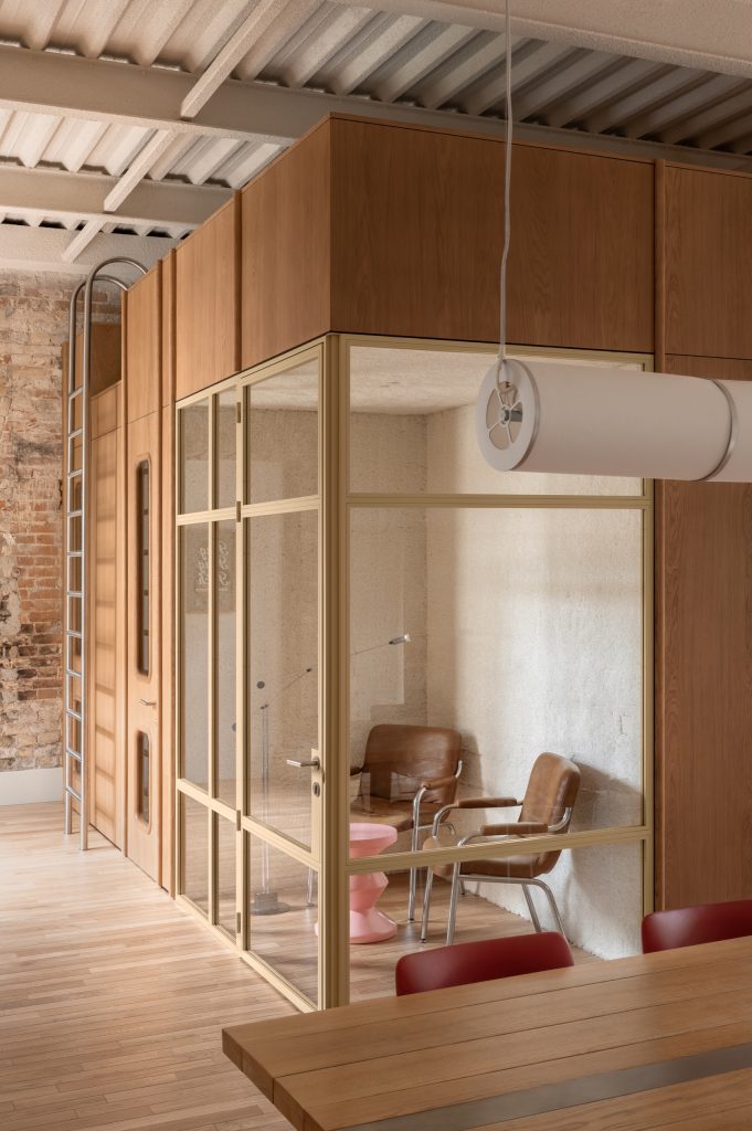 Oak-clad cube with a mezzanine above, a steel pool ladder up its side and a brass-framed glass meeting room within