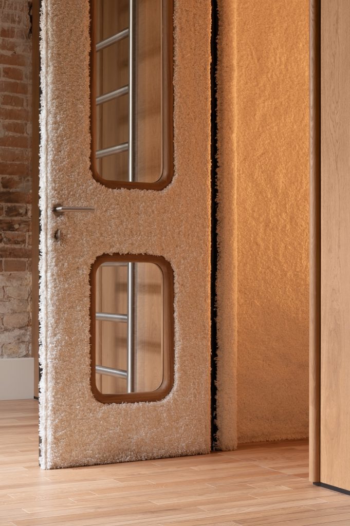 Door upholstered in cream shearling with rounded glass panels, set into an ochre-lined opening