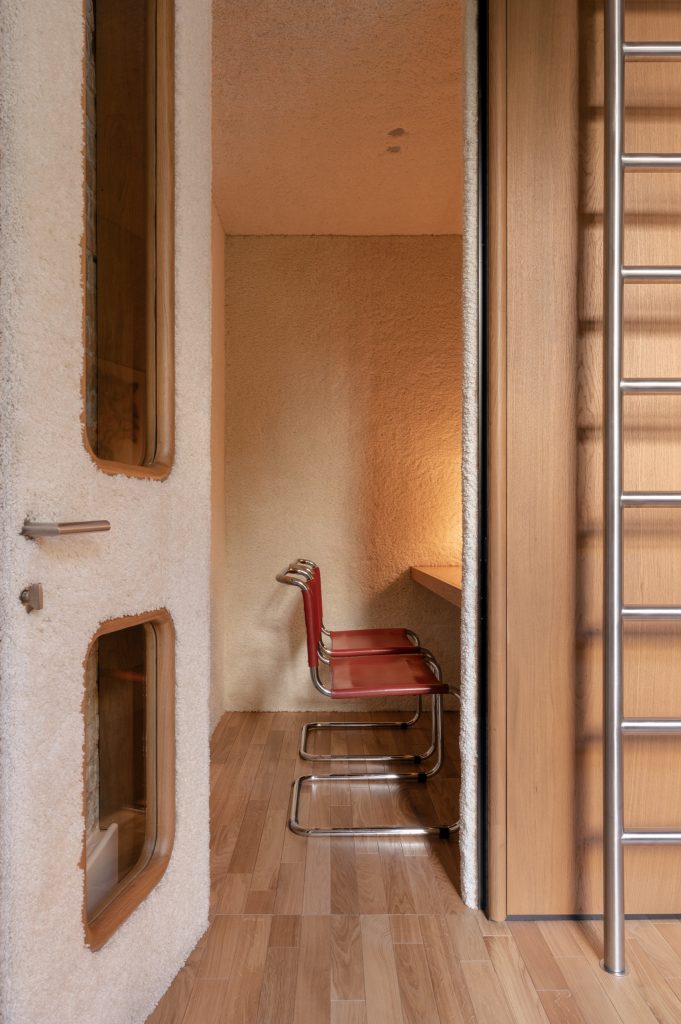 Interior of a shearling-lined booth with a red leather cantilever chair and a narrow timber ledge