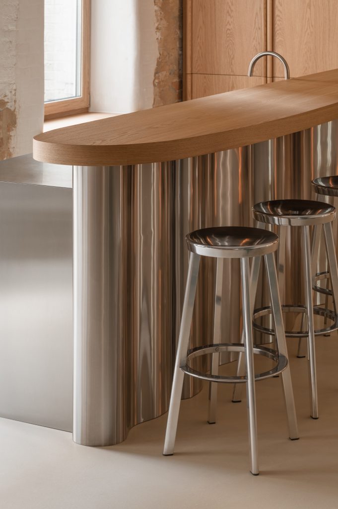 Detail of the wavy polished-steel bar counter with its oak top and chrome stools