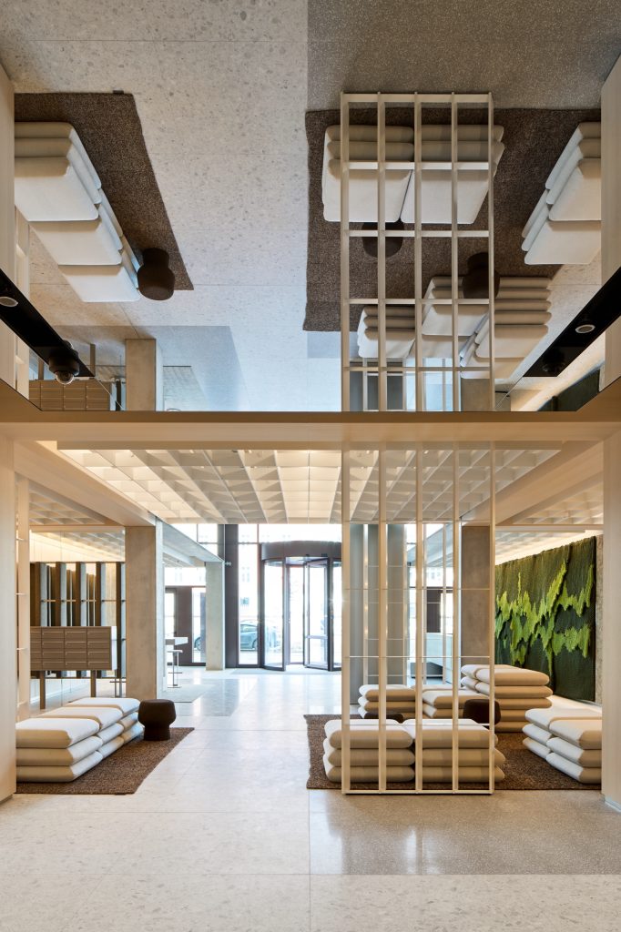 View through the lobby to the revolving door, the mirrored ceiling doubling the cushion lounges and post boxes
