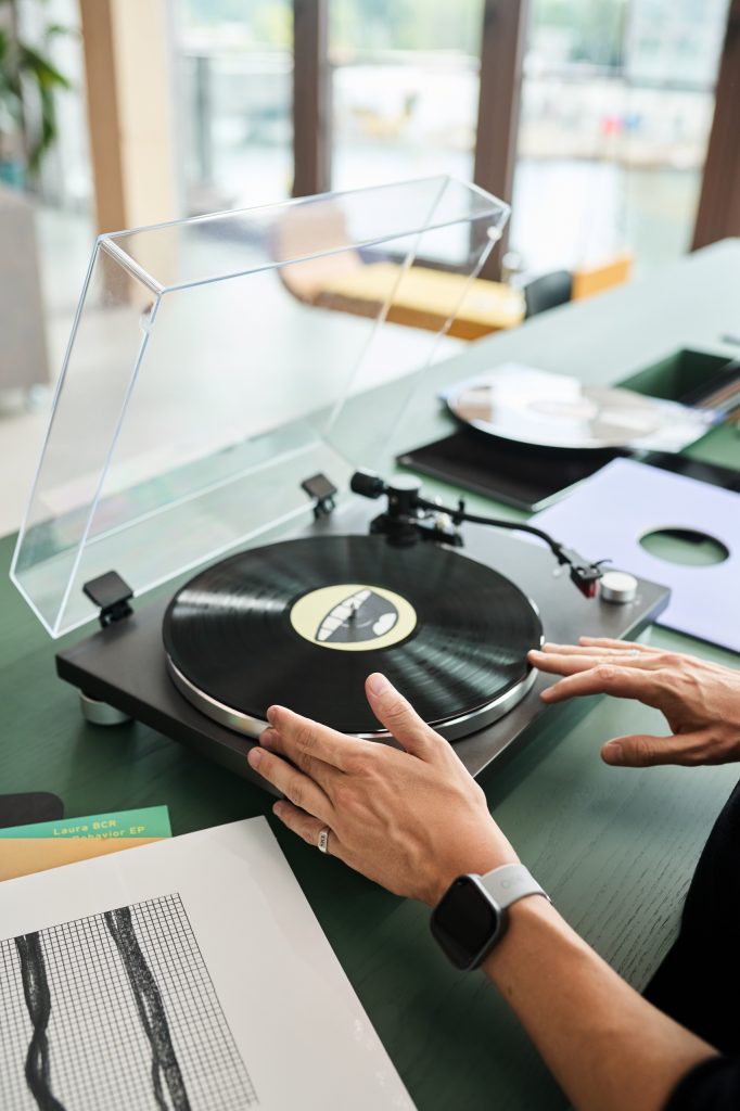 Hands cueing a record on the turntable set into the green DJ desk