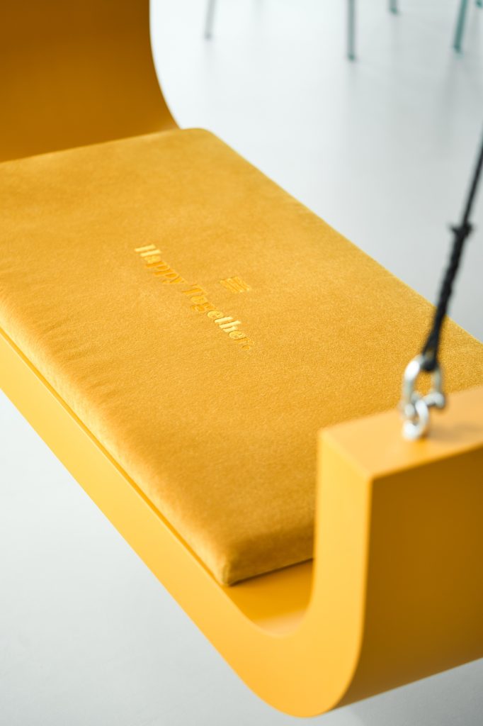 Mustard swing seat with Happy Together embroidered on its velvet cushion
