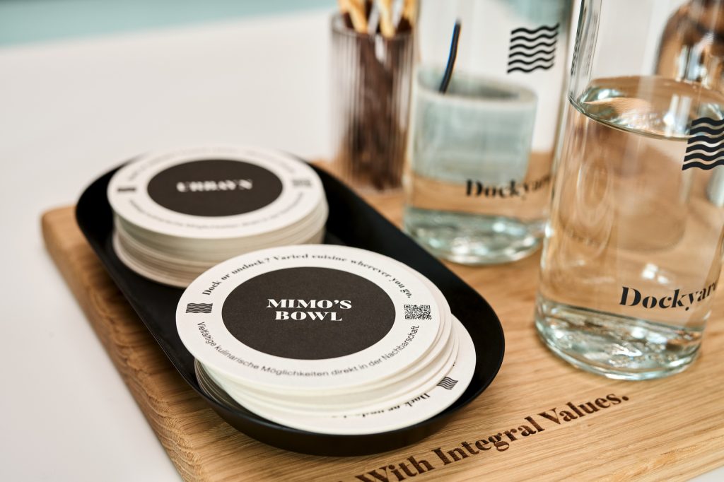 Branded beer mats and Dockyard water glasses on an engraved oak board