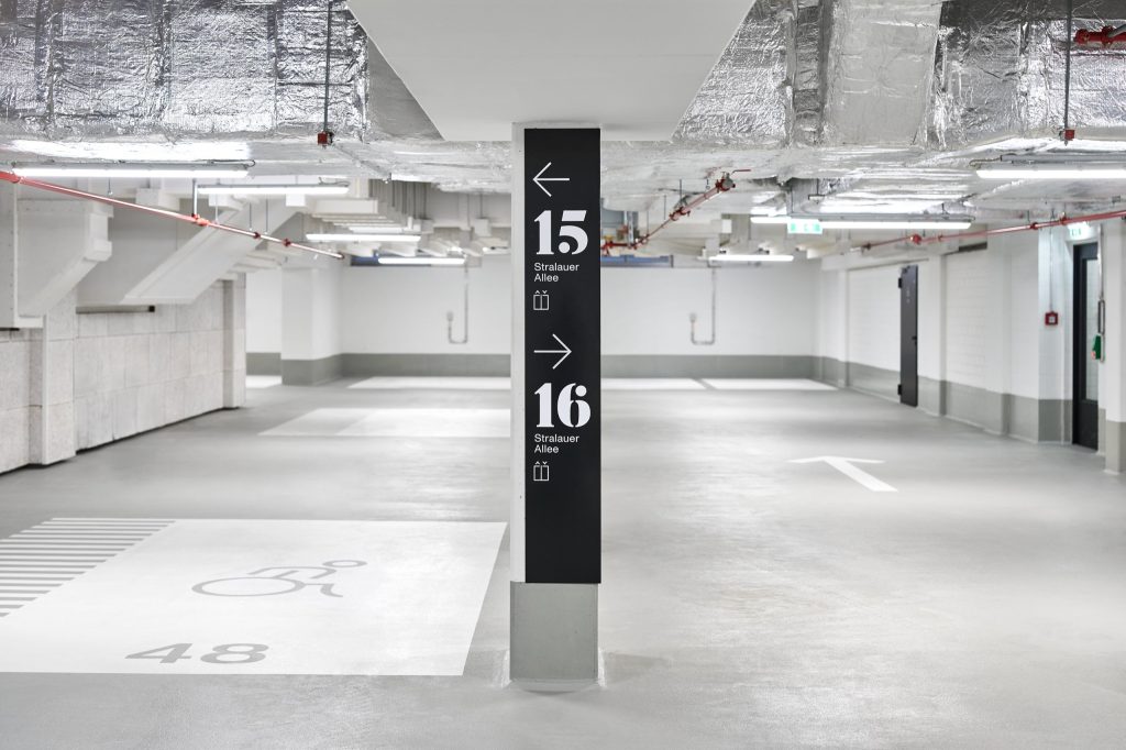 Black pylon splitting directions to 15 and 16 Stralauer Allee in the empty garage, an accessible bay numbered 48