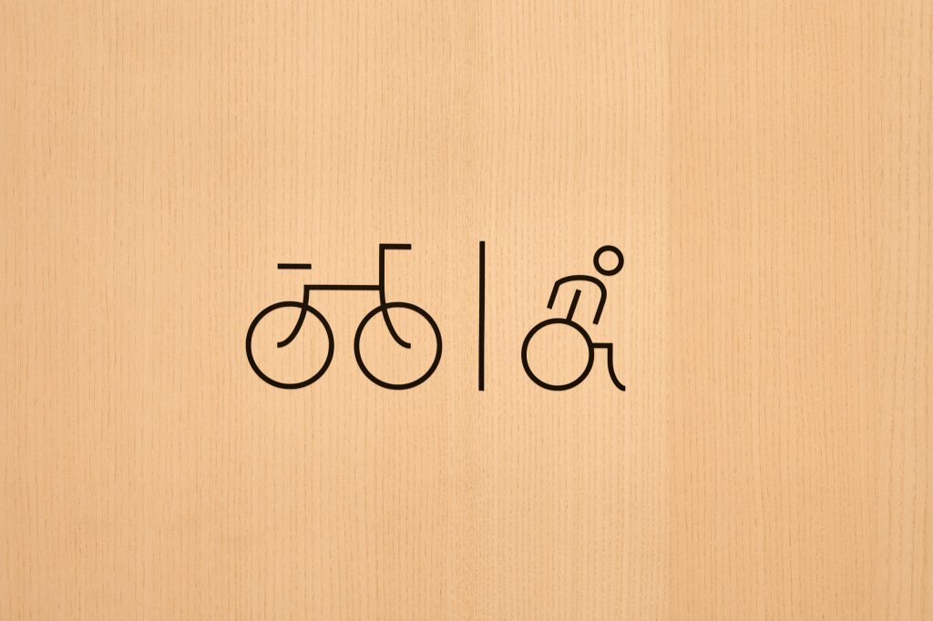 Bicycle and wheelchair pictograms in thin black line on a pale timber door