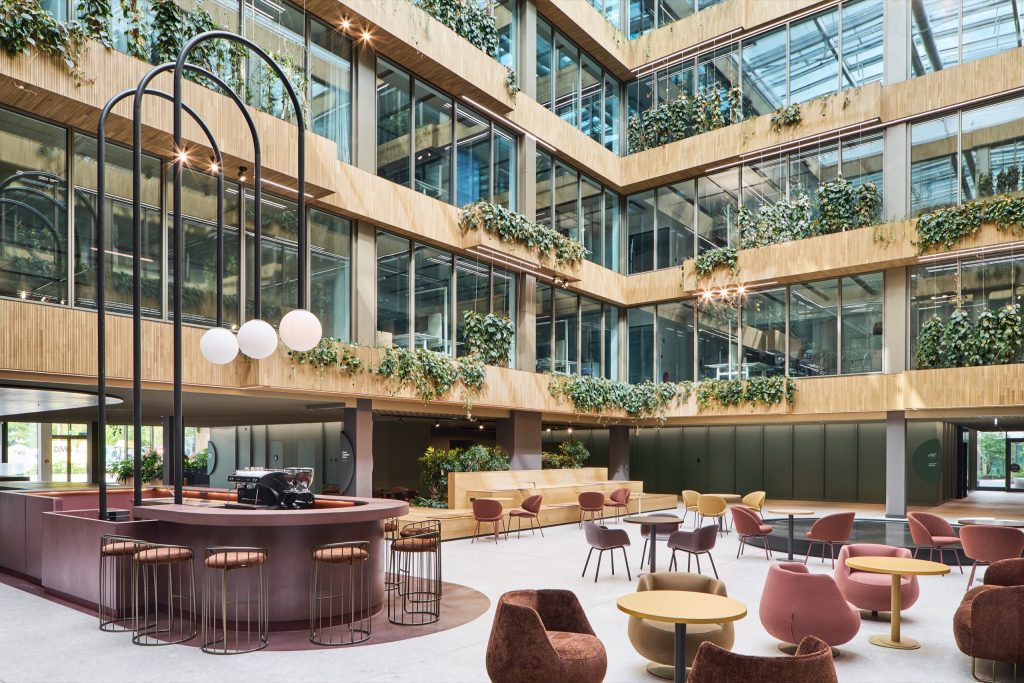 Oxblood cafe bar with caged stools beneath arched globe lamps, planted balconies rising behind