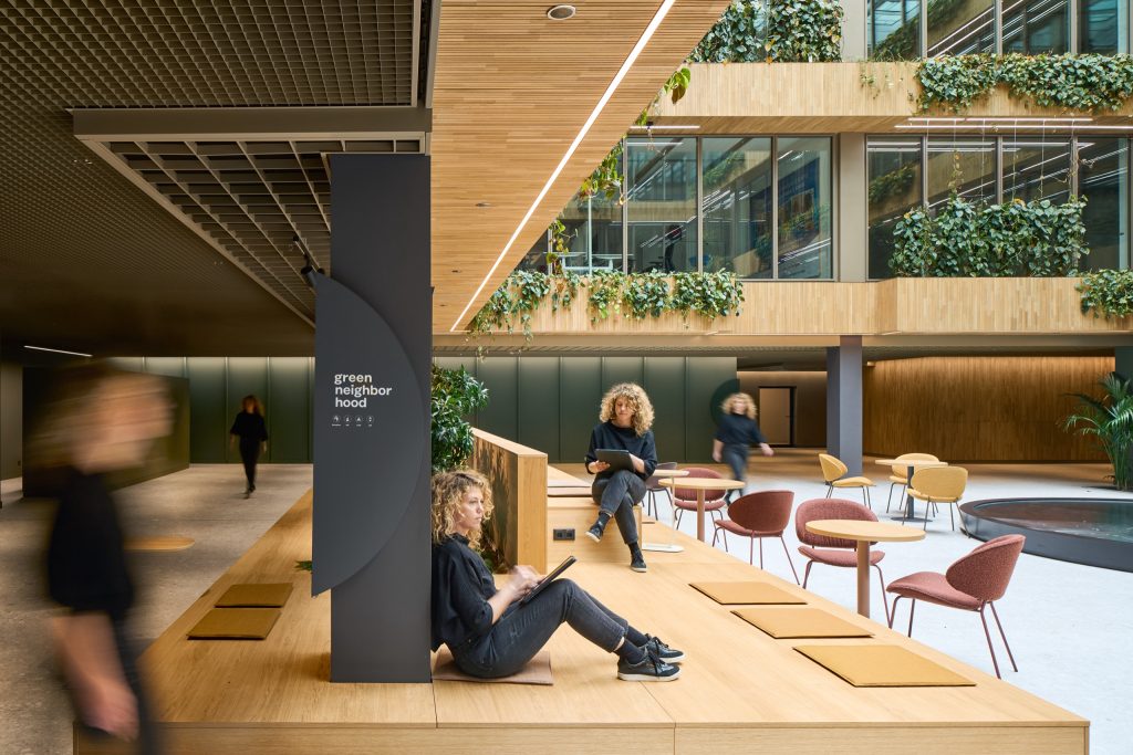 Tiered timber work platform with seat pads and side tables, people working above the water feature