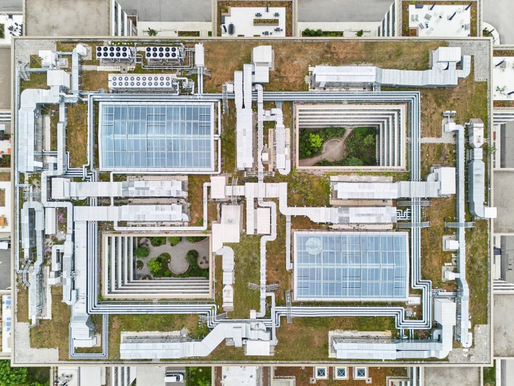 Aerial view of the campus roof: two glazed atrium roofs and two planted open courtyards cut into the orthogonal block