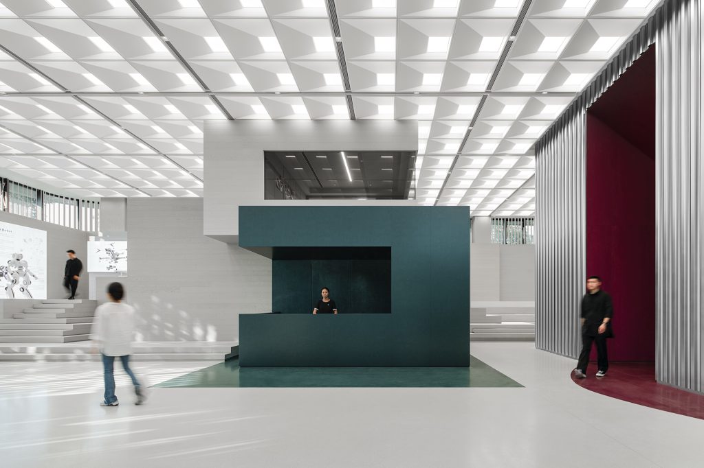 Ground-floor lobby with reception desk, tiered seating steps and metal-slat screens