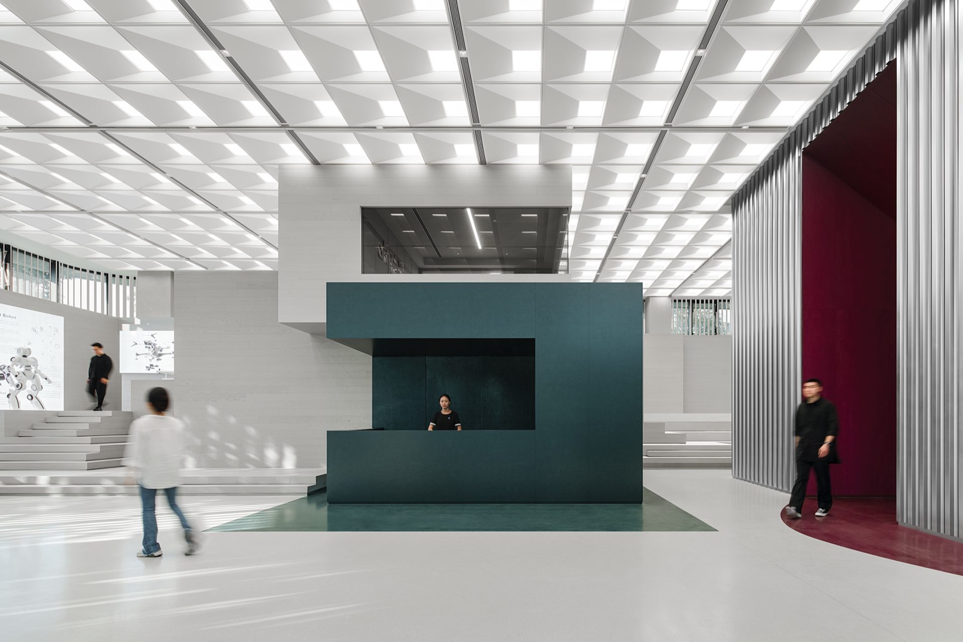 Ground-floor lobby with reception desk, tiered seating steps and metal-slat screens