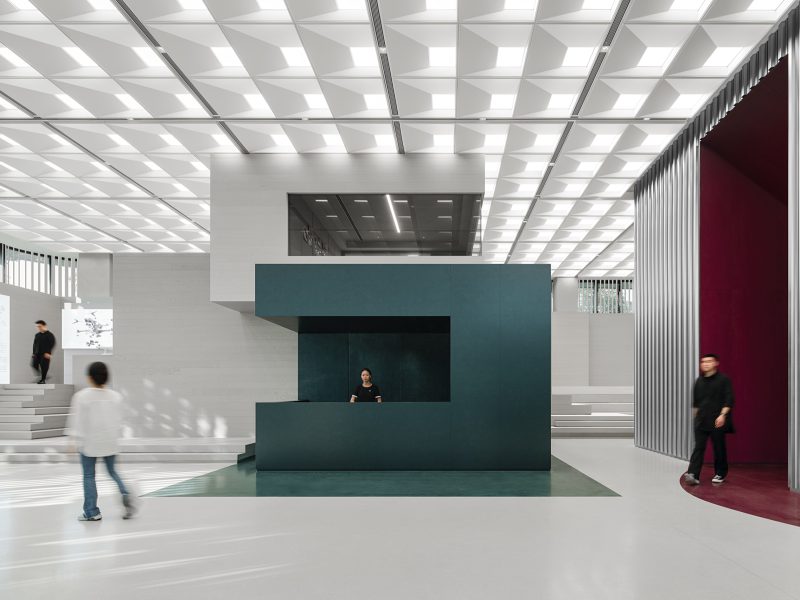 Ground-floor lobby with reception desk, tiered seating steps and metal-slat screens