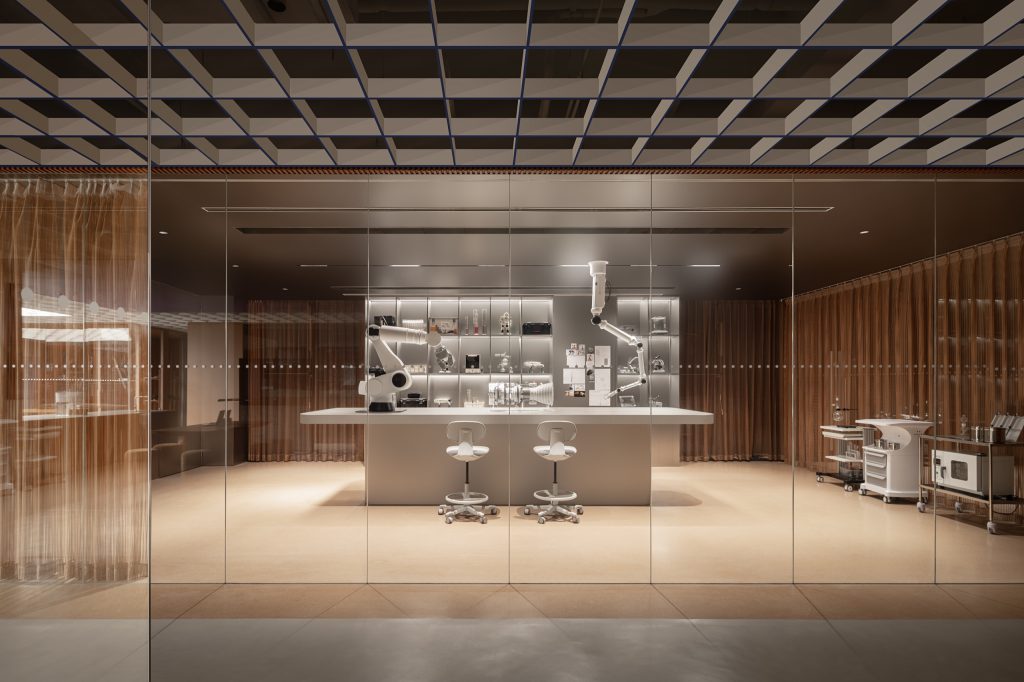 Glass-walled R&D lab with robotic arms at a central bench, surrounded by bronze mesh curtains