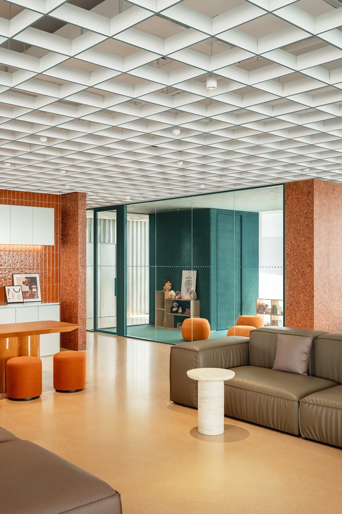 Felt-lined family room behind glass, with toy shelves and orange poufs