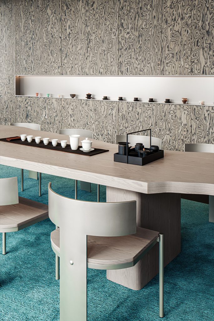 Tea room with a pale timber table set for gongfu tea, curved metal chairs and a ceramics display niche