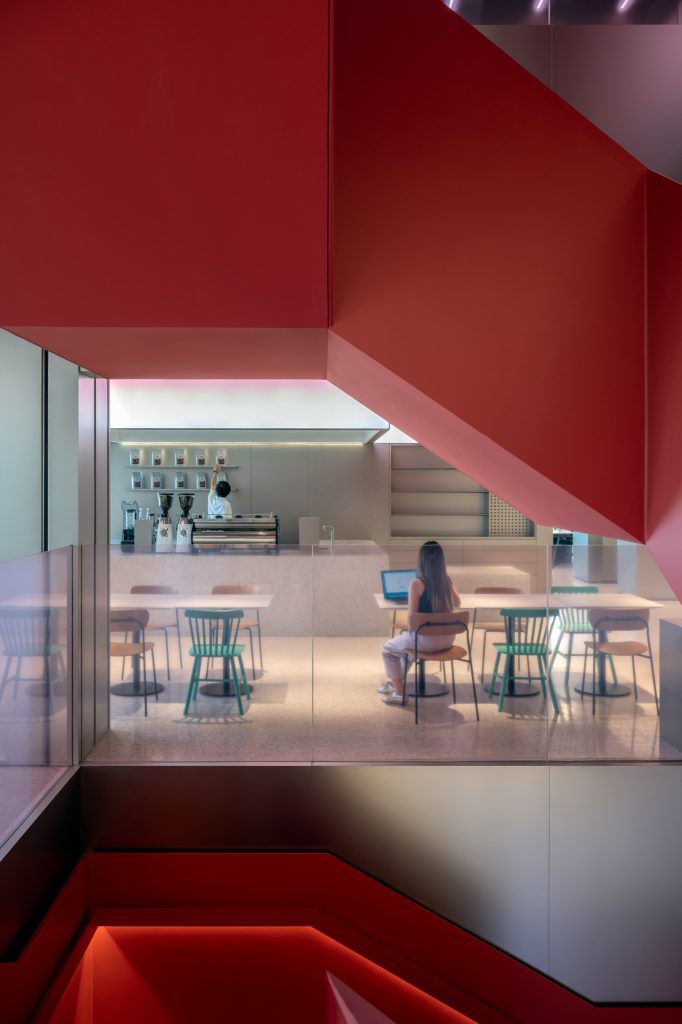 View beneath the red staircase into the employee cafe, with espresso machines and mint-green chairs
