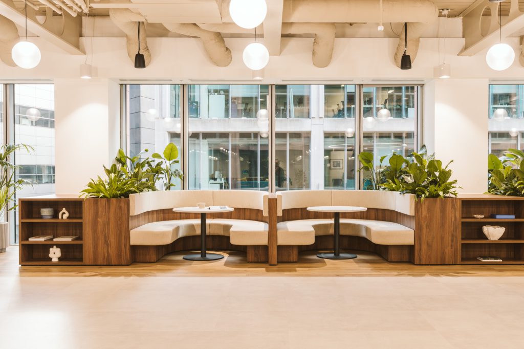Two semi-circular booths built into walnut joinery with planters, facing the window line