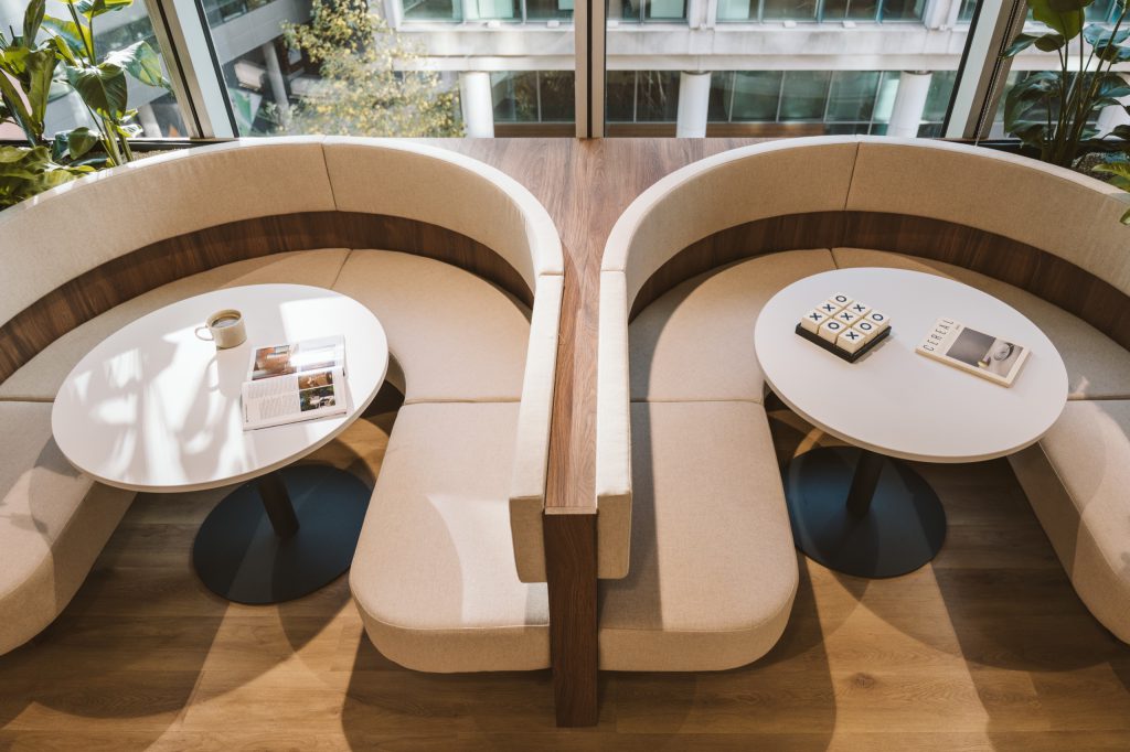 Looking down on two semi-circular booths with round white tables, coffee and a noughts-and-crosses set