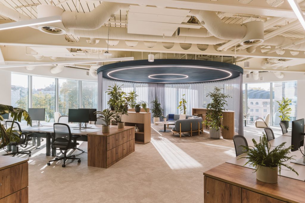Open workspace with white desks and timber lockers, a navy circular canopy with ring lights beyond