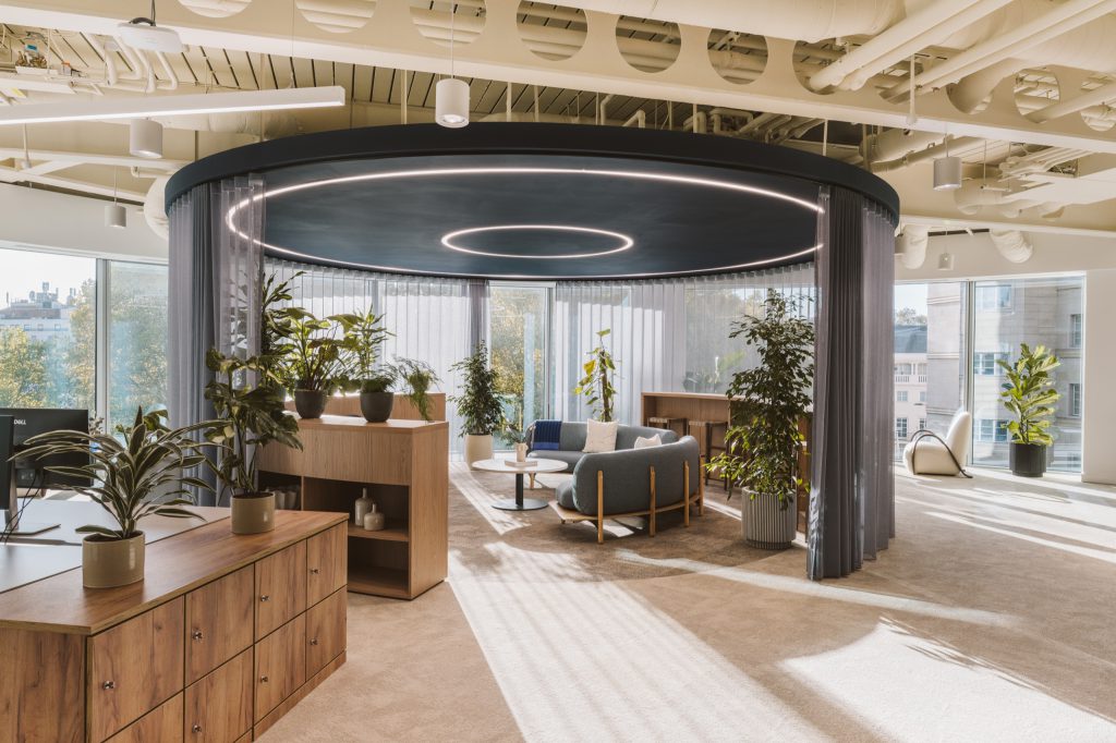 Circular collaboration space beneath a navy canopy with ring lighting, wrapped in sheer curtains and planting