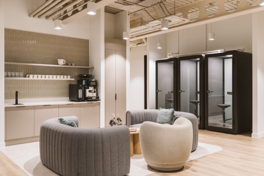 Tea point beside three black phone booths, curved sofas gathered around an oak table