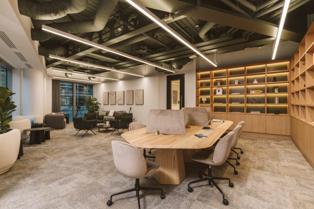 The Library toward its lounge corner, green wing chairs beneath framed artwork